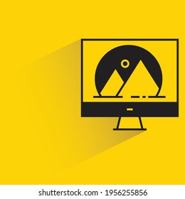 desktop computer and graphic design with shadow on yellow background