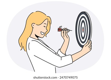 Determined woman throws darts at target for concept of business success and achieving set goals. Goal oriented businesswoman with darts board smiling setting and achieving ambitious goals