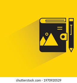 diary book and pen with shadow on yellow background