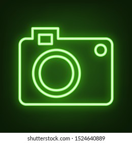 Digital camera sign. Green neon icon in the dark. Blurred lightening. Illustration.