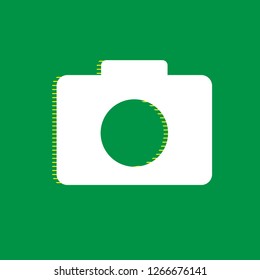 Digital camera sign. Vector. White flat icon with yellow striped shadow at green background.