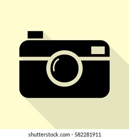 Digital photo camera sign. Black icon with flat style shadow path on cream background.