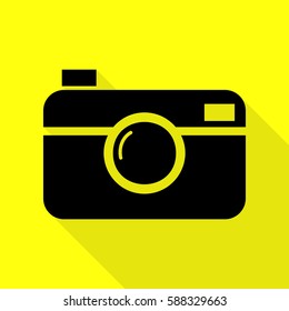 Digital photo camera sign. Black icon with flat style shadow path on yellow background.