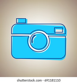 Digital photo camera sign. Vector. Sky blue icon with defected blue contour on beige background.