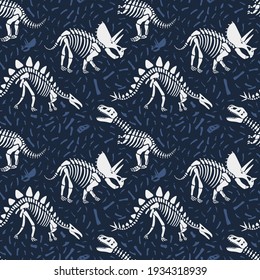 Dinosaurs skeletons seamless pattern on dark blue background with bones. Children textile with dinos skulls.