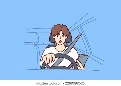 Distracted man driver with phone sits behind wheel of car and gets scared sees obstacle on road or sharp turn. Shocked driver not following traffic rules using smartphone while driving 