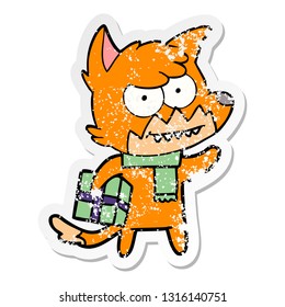 distressed sticker of a cartoon grinning fox with christmas present