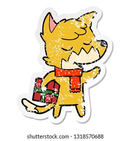 bedrückter Aufkleber eines freundlichen Cartoon-Fuchses mit Weihnachtsgeschenk
