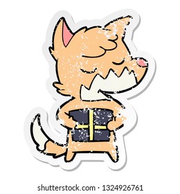 distressed sticker of a friendly cartoon fox with christmas present