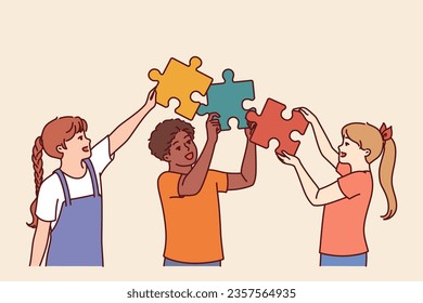 Diverse kids hold puzzle pieces as together solve problem together and demonstrate teamwork in learning process. Friendly multiethnic kids learn communication and collaboration to achieve goals