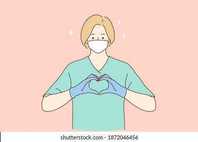 Doctors help and love, safety and care during coronavirus pandemic concept. Woman professional medic or nurse in protective face mask, gloves and green working uniform forming heart with fingers 