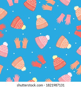 Doodle bright orange and pink gloves, wool hats, white dots on blue background. Seamless winter clothes pattern. Suitable for packaging, textile, wallpaper.