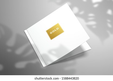 A double postcard with a gold foil lettering frame lies on the surface. Realistic mockup for design with shadow from Monstera leaves