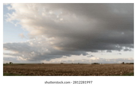 Dramatic landscape featuring storm clouds gathering above rural farmland at sunset. Wide view of agricultural field with stormy sky creating moody and atmospheric lighting.
