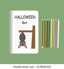 Drawing of a bat hanging from a tree in a school notebook, as a symbol of Halloween, along with the pencils used to color it.