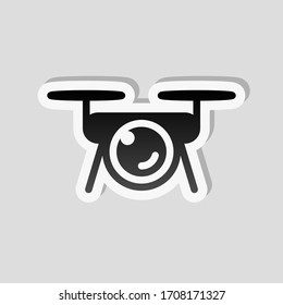 Dron con cámara, logo técnico. Estilo adhesivo con borde blanco y sombra simple sobre fondo gris