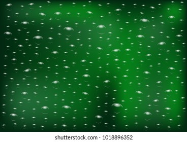 Drops of rain on an evening summer day on a glass of trees blurred green background.