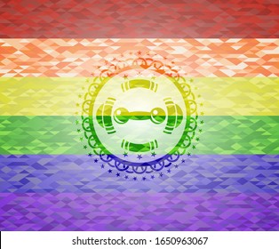 ícono de timbre dentro del emblema sobre fondo de mosaico con los colores de la bandera LGBT