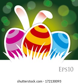 Dyed Easter eggs in the grass and bunny ears against green background