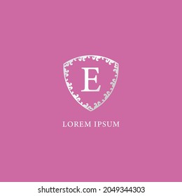 E Letter Intial logo design template isolated on pink color background. Luxury silver decorative floral shield illustration. Suitable for Insurance, fashion and beauty product.