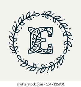 E letter logo consisting of floral pattern in a circle laurel wreath. Linear heraldic vector font. Can be used for boutique, cafe, restaurant, royalty, hotel, jewelry or sport industry.