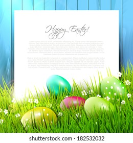 Easter background with colorful eggs in grass and empty paper