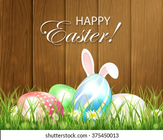 Easter background with multicolored eggs and rabbit ears in the grass on wooden background, illustration.