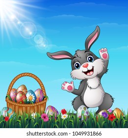Easter bunny with Easter basket full of decorated Easter eggs in a grass field