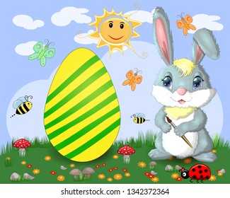 Easter bunny with a brush paints huge Easter egg on glade, the sun, butterflies, spring. Copy space