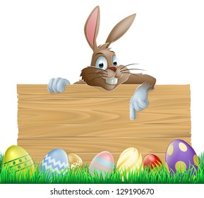 An Easter bunny character peeking over a wooden Easter sign pointing his finger down at space for your message. Surrounded by decorated chocolate Easter eggs