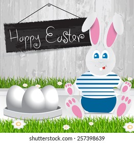 Easter bunny. Happy Easter . White Easter eggs.The grass with a wooden fence and flowers.