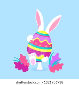 Easter bunny holding a big paschal egg. Funny rabbit walks on the lawn