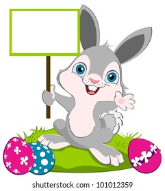 Easter Bunny holding a board and weaving, colorful eggs on the ground.