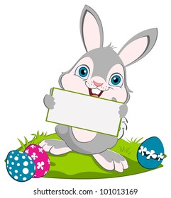 Easter Bunny holding greeting card and smiling. Tree eggs on the ground.