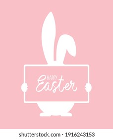 Easter bunny is holding a sign with a greeting at pink background.