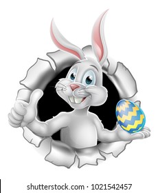 Easter bunny rabbit breaking background, holding a chocolate Easter egg and giving a thumbs up