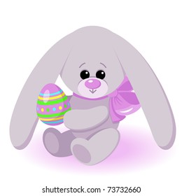 Easter bunny / The easter bunny sits and holds an easter egg in paws.