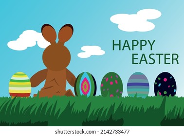 
EASTER BUNNY SITTING ON THE GRASS WITH COLORED EGGS
