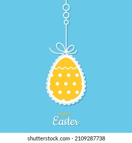 Easter card. Colorful decorated openwork yellow Easter egg hangs on bright blue background. Ribbon with decorations. Happy Easter inscription. Cut out Paper egg. Vector illustration