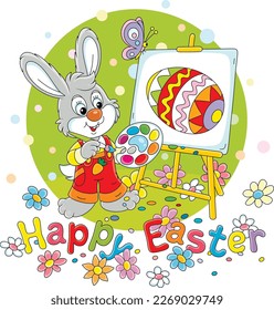 Easter card with a happy little bunny drawing a decorated gift egg with bright paints on an easel on a pretty spring lawn with flowers, vector cartoon illustration on white