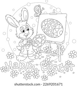 Easter card with a happy little bunny drawing a decorated gift egg with a paintbrush and paints on an easel on a pretty spring lawn with flowers, outlined vector cartoon illustration