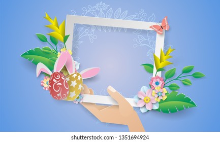 Easter day frame with paper flower in hand on blue background.
