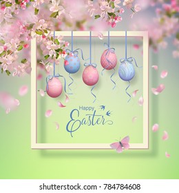 Easter decorative frame with blooming spring branches, hanging painted eggs and falling petals