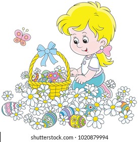 Easter egg hunt. Little girl with a decorated basket collecting colorfully painted eggs among white daisies