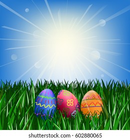 Easter eggs on the green grass against the blue sky with the sun