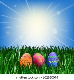 Easter eggs on the green grass against the blue sky with the sun