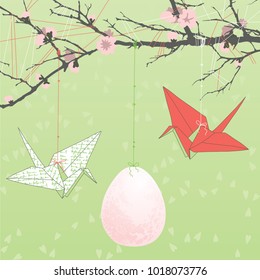 Easter eggs and two paper cranes hanging on tree branch