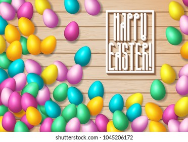 Easter frame with shiny colorful eggs spread over wooden background