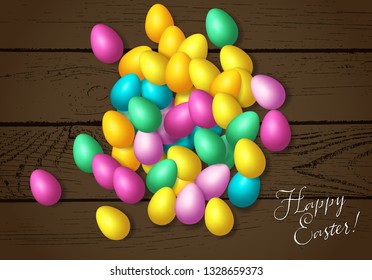 Easter frame with shiny colorful eggs spread over wooden background