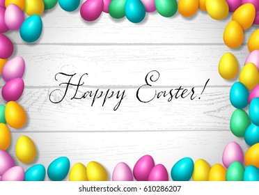 Easter frame with shiny colorful eggs spread over wooden background